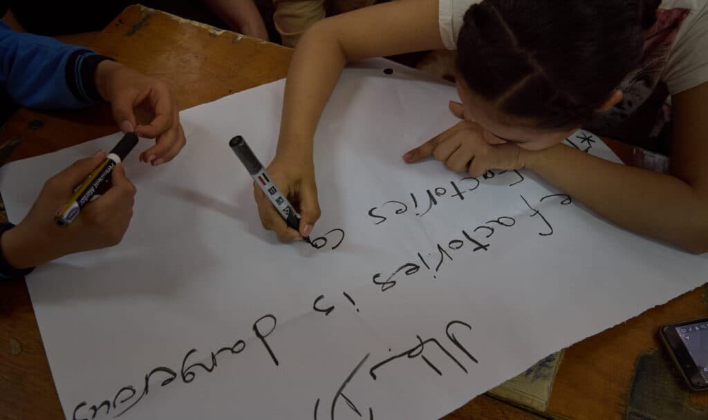 Två barn som skriver på ett stort papper