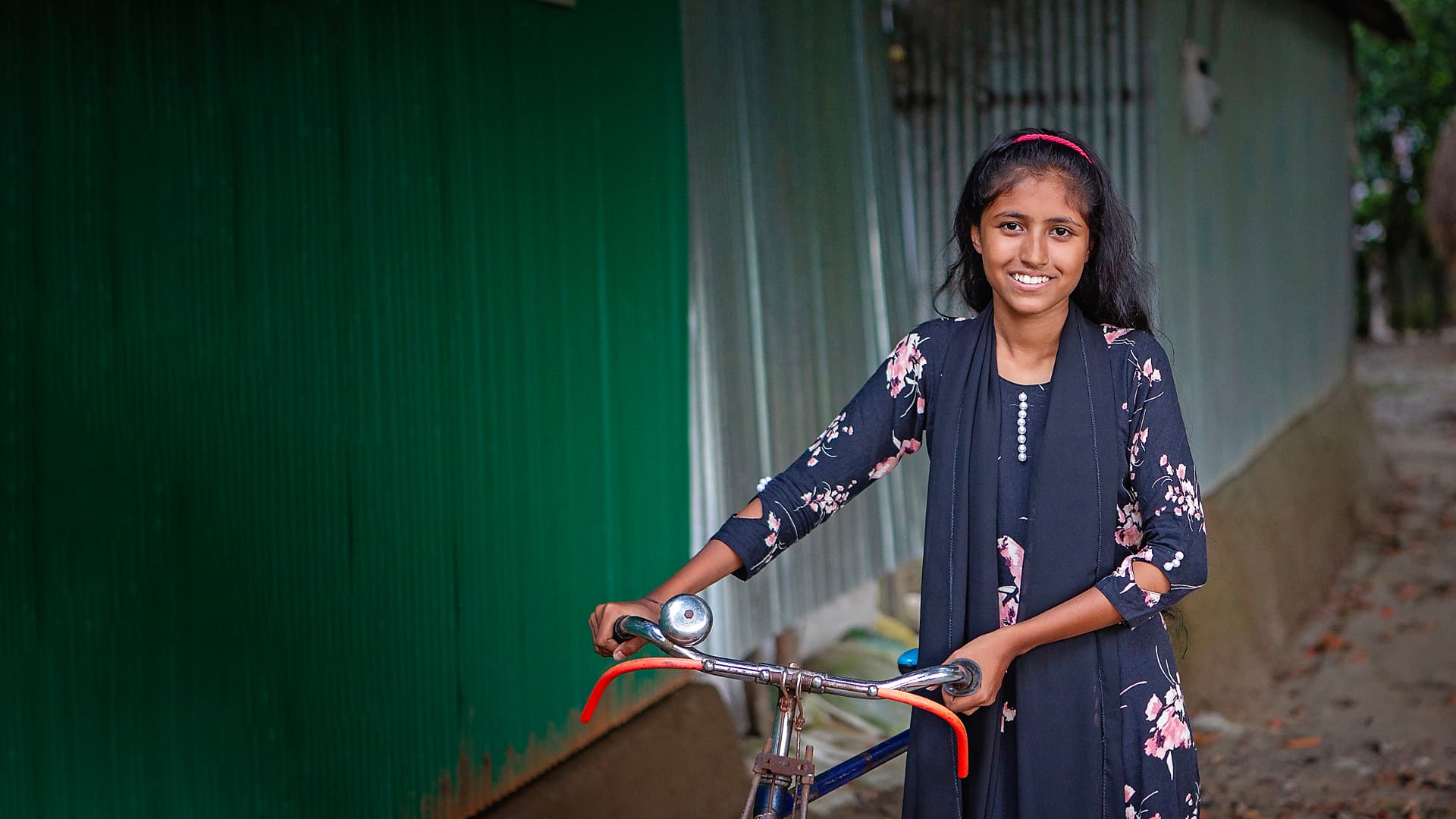 Photo: Diakonia A girl with long dark hair and a dark dress with a bicycle.