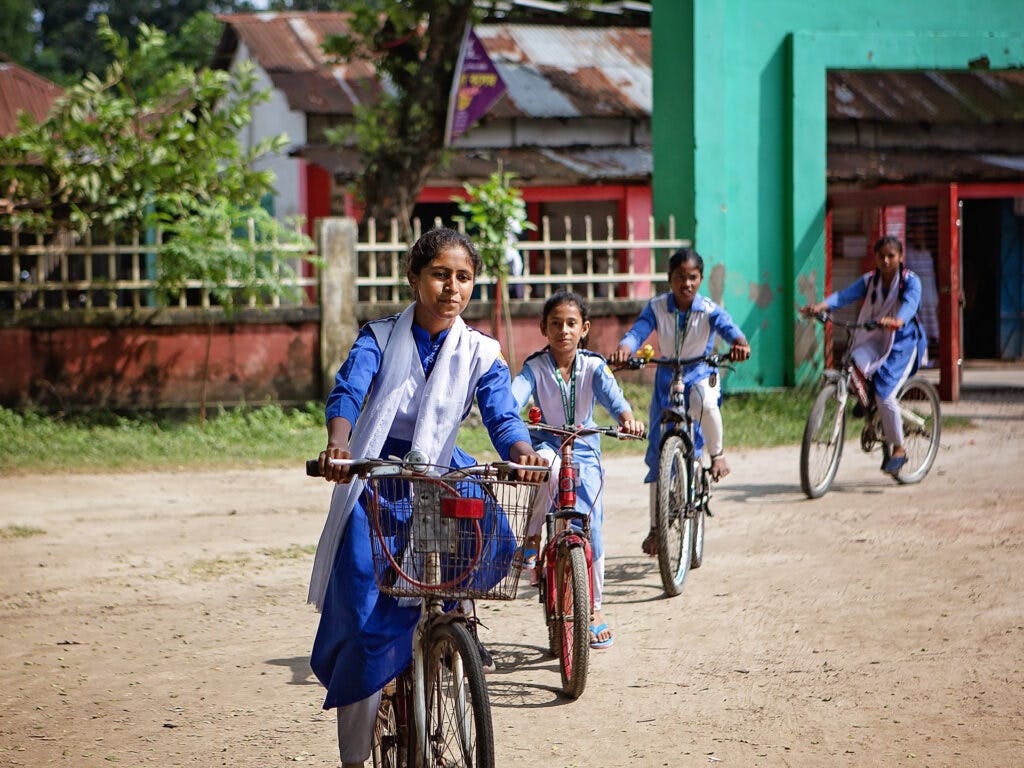 En flicka i skoluniform som cyklar på en skolgård.