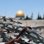 Barbed wire and in the background the golden dome of the Dome of the Rock in Jerusalem.