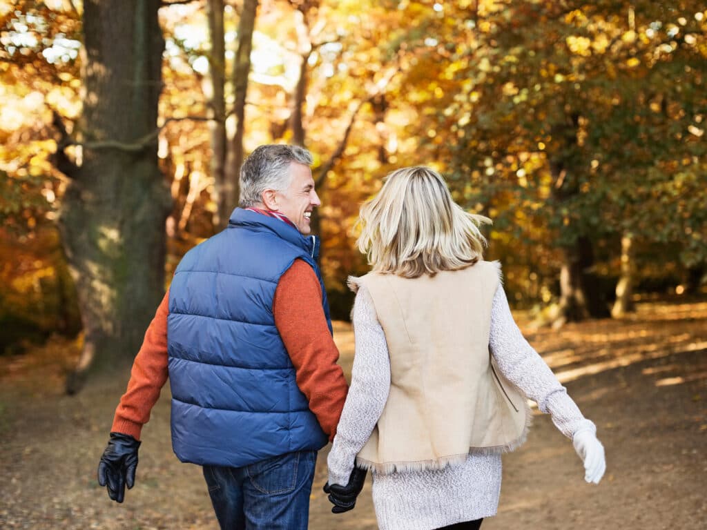 Ett par i 50-årsåldern med ryggarna mot kameran som håller hand.
