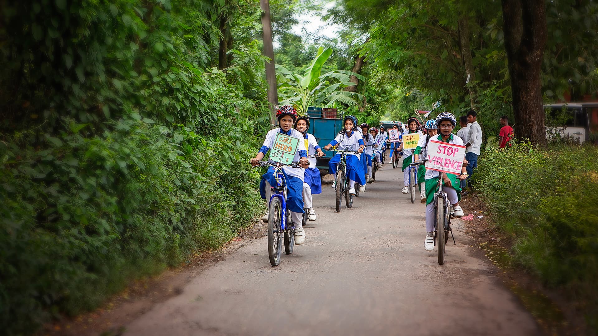 Foto: Diakonia En grupp flickor i skoluniform cyklar tillsammans med plakat på cyklarna.