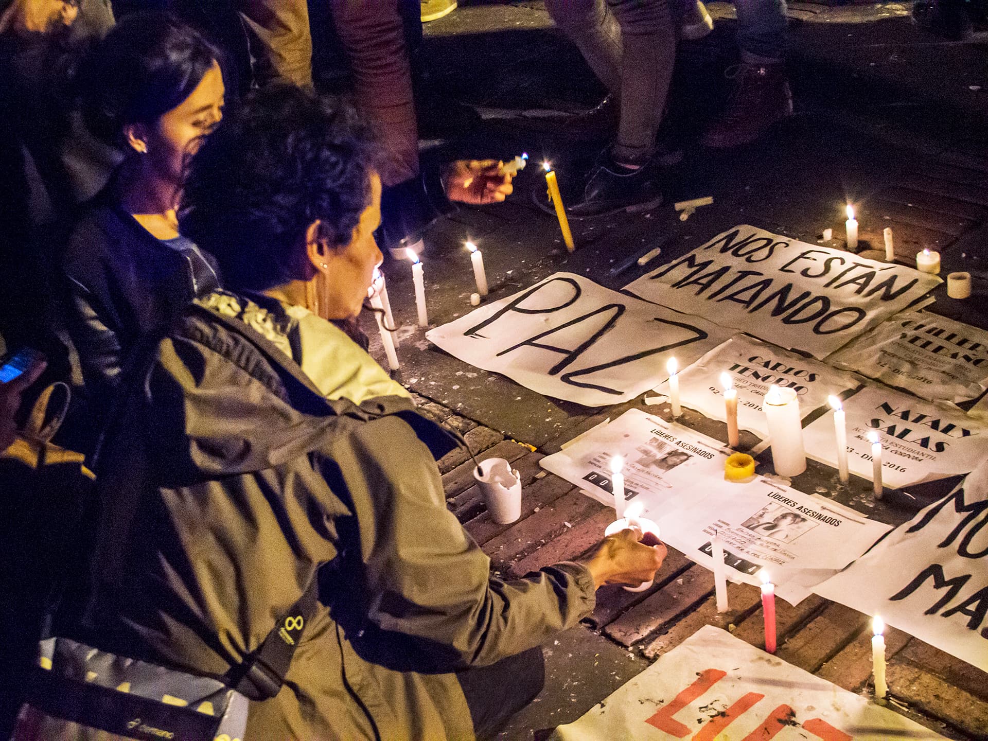 Photo: Diakonia Two women lighting candles next to signs promoting peace.