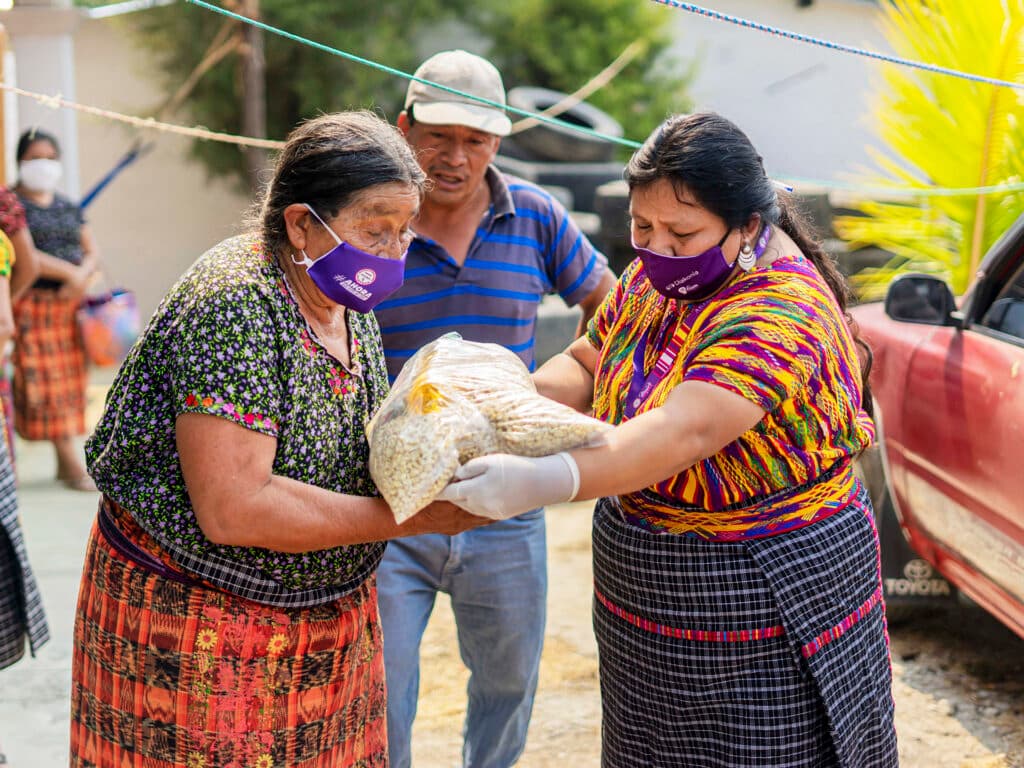 Photo: AGIMS Two Guatemalan women wearing face masks handling food packages