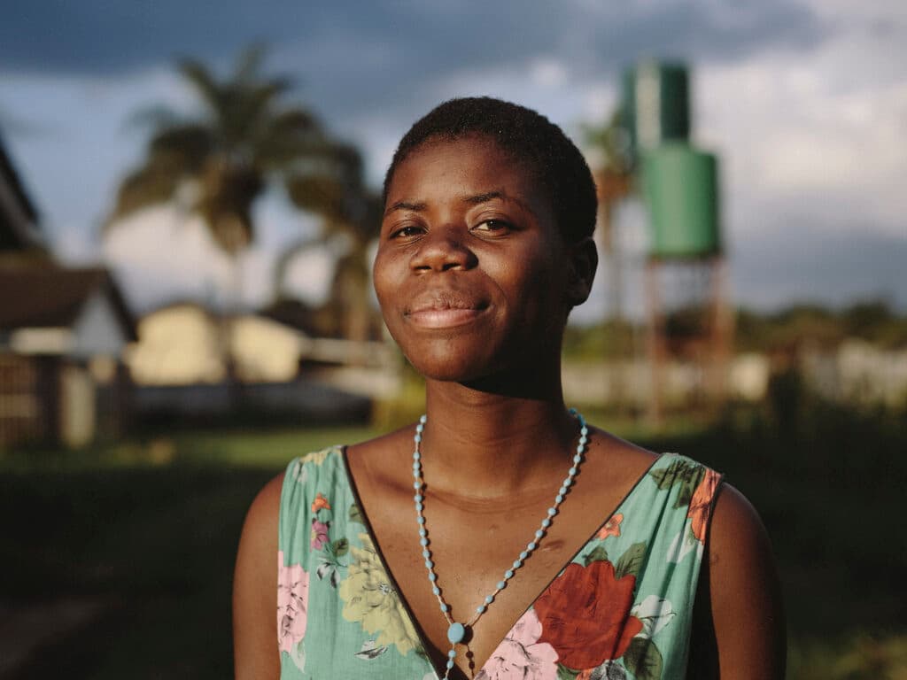 Photo: Anna Hugosson A portrait of a Zimbabwean woman in sunset. In the background there are some houses and trees.