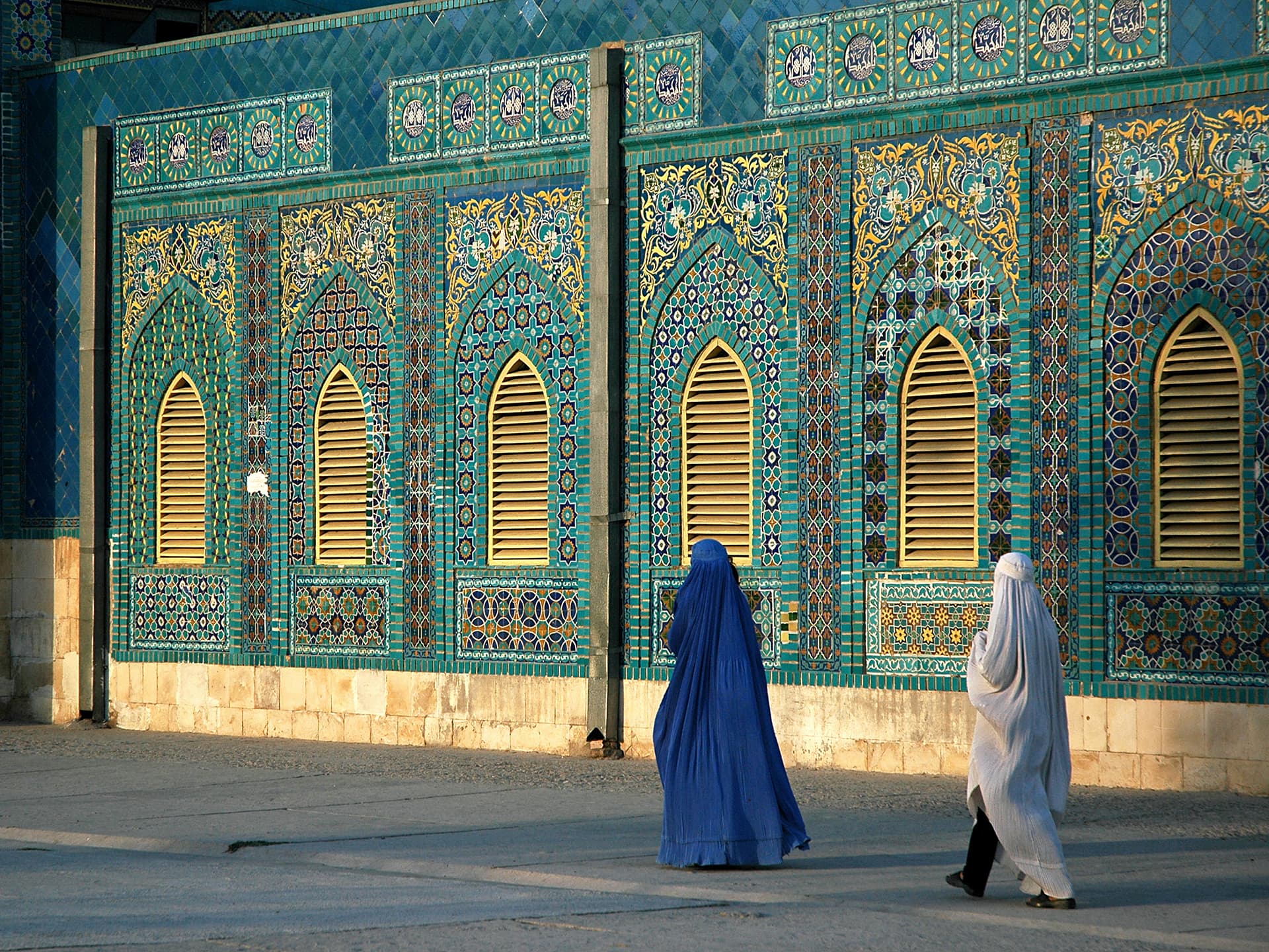 Photo: Jonathan Wilson Two women wering burqas seen from behind, walking past a mosque.