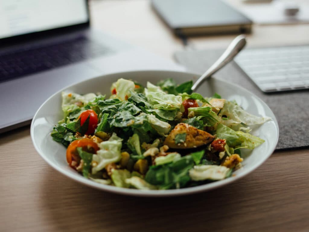 En tallrik med sallad på ett skrivbord