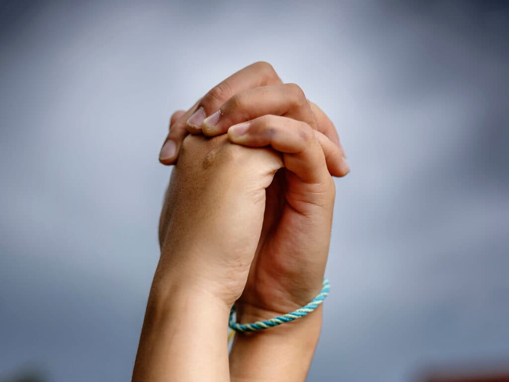 Närbild av två händer som håller i varandra i luften.