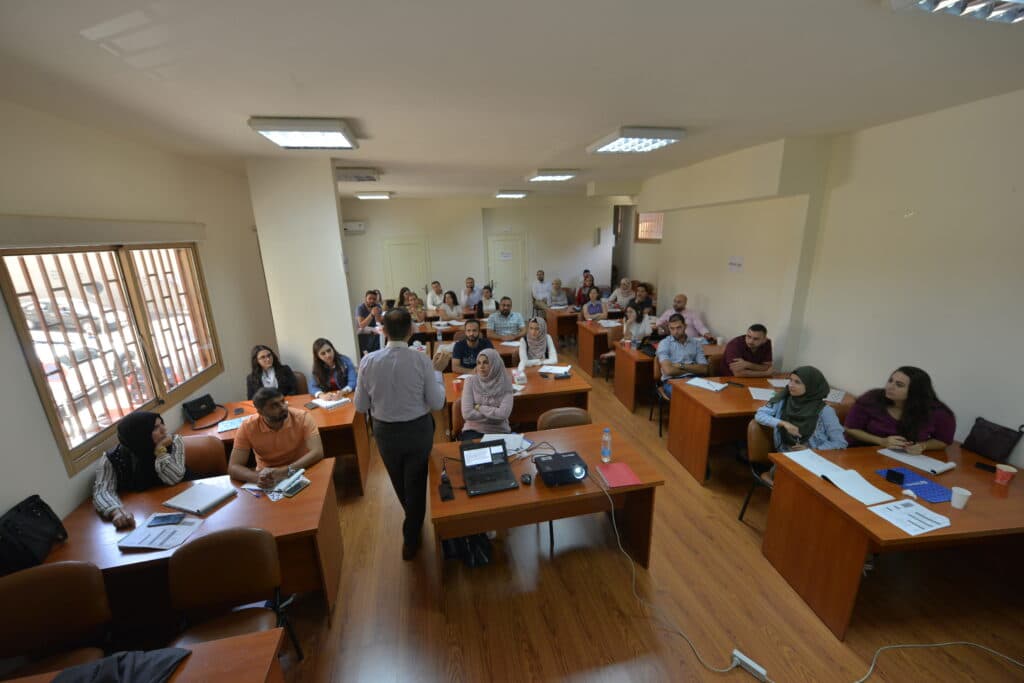 A classroom with many students listening to a teacher. A classroom with many students listening to a teacher.