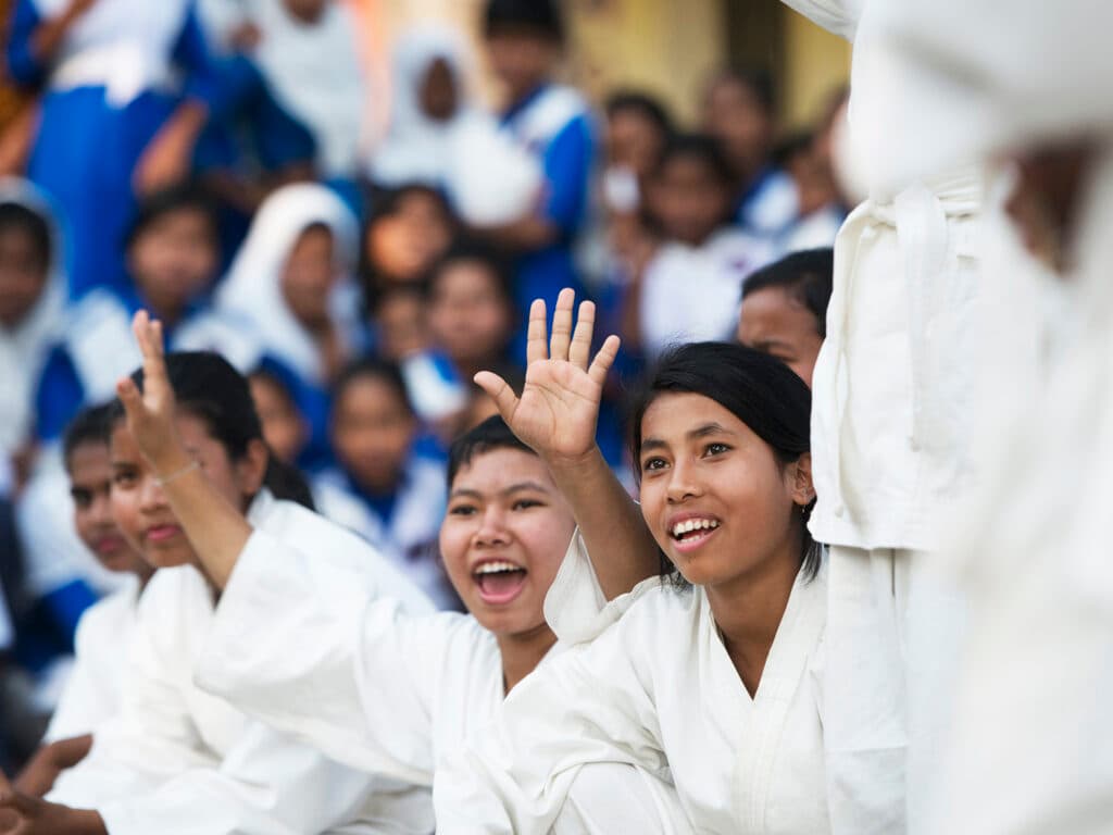Photo: Gustav Hugosson Young women in Karate suits sitting in a group cheering.