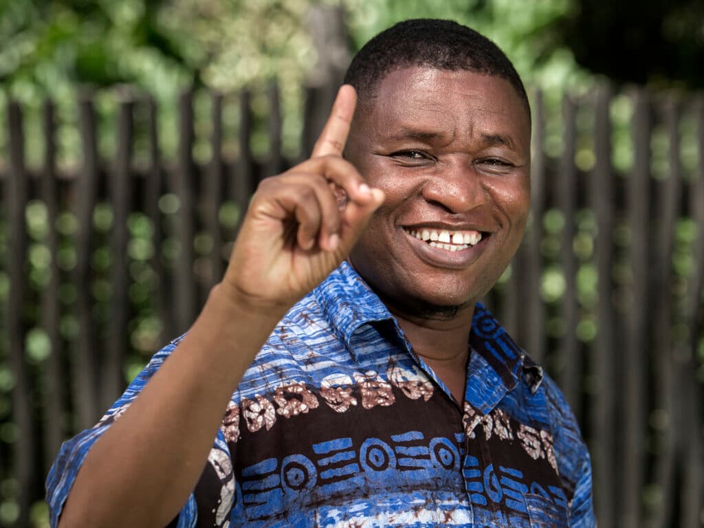 Photo: Markus Marcetic A smiling Kenyan man with his finger lifted, looking in to the camera.