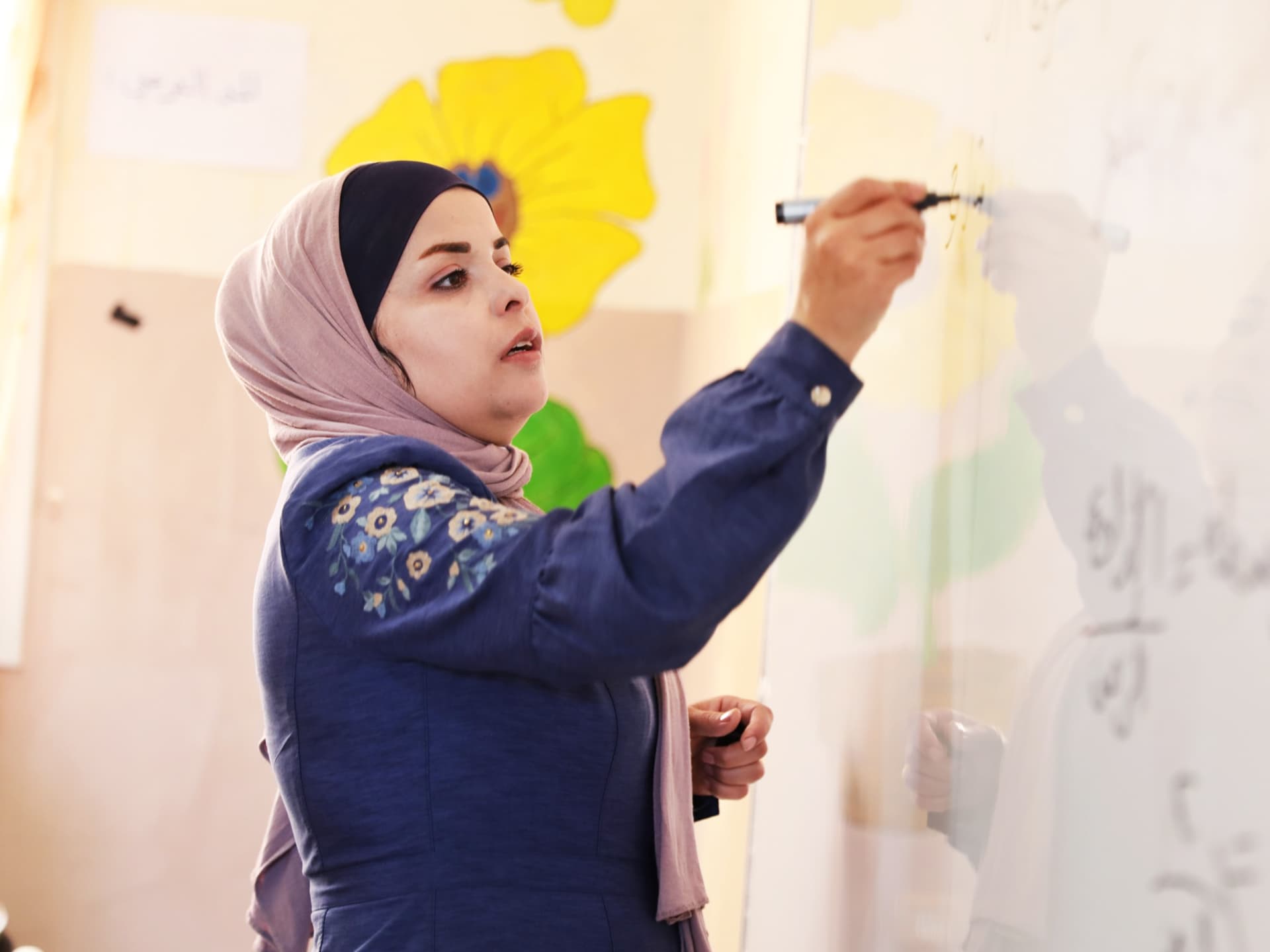 Photo: Diakonia A woman wearing a hijab writing on a white board.